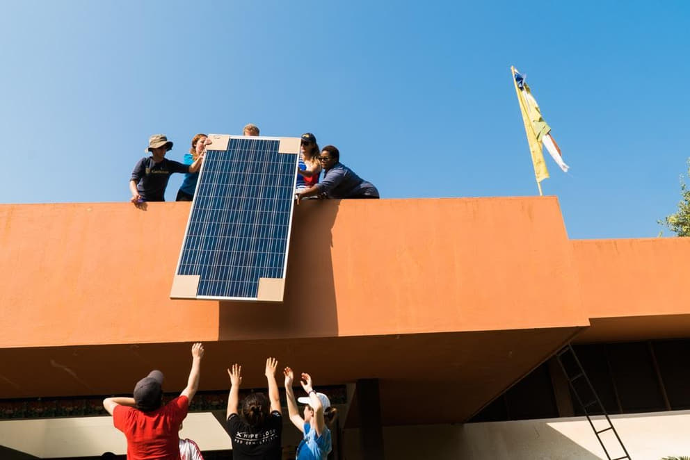 Installing solar panels on the roof of the Pavilion of Tibetan Culture, Auroville