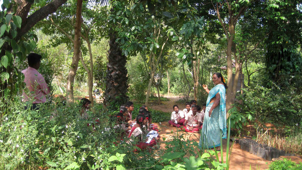 A group of school children in the herbal garden with Kaamachi, one of the educators at the Botanical Gardens